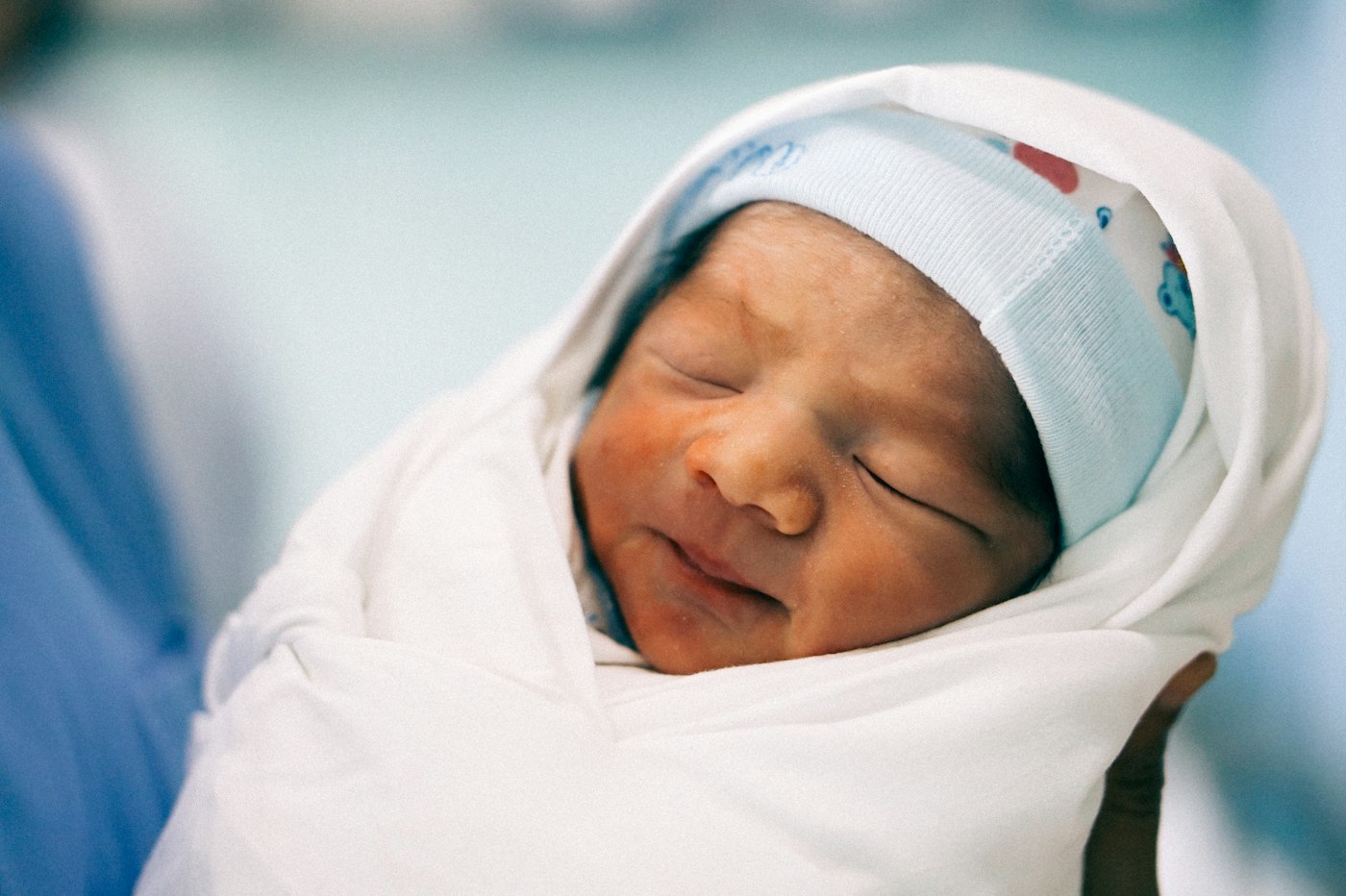 Newborn wrapped snugly in a white muslin swaddle